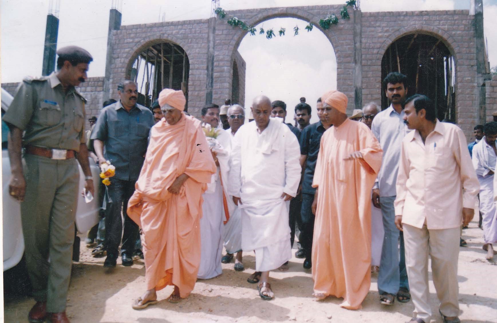 A Swamiji walking with public guests and security personnel at the Kshetra