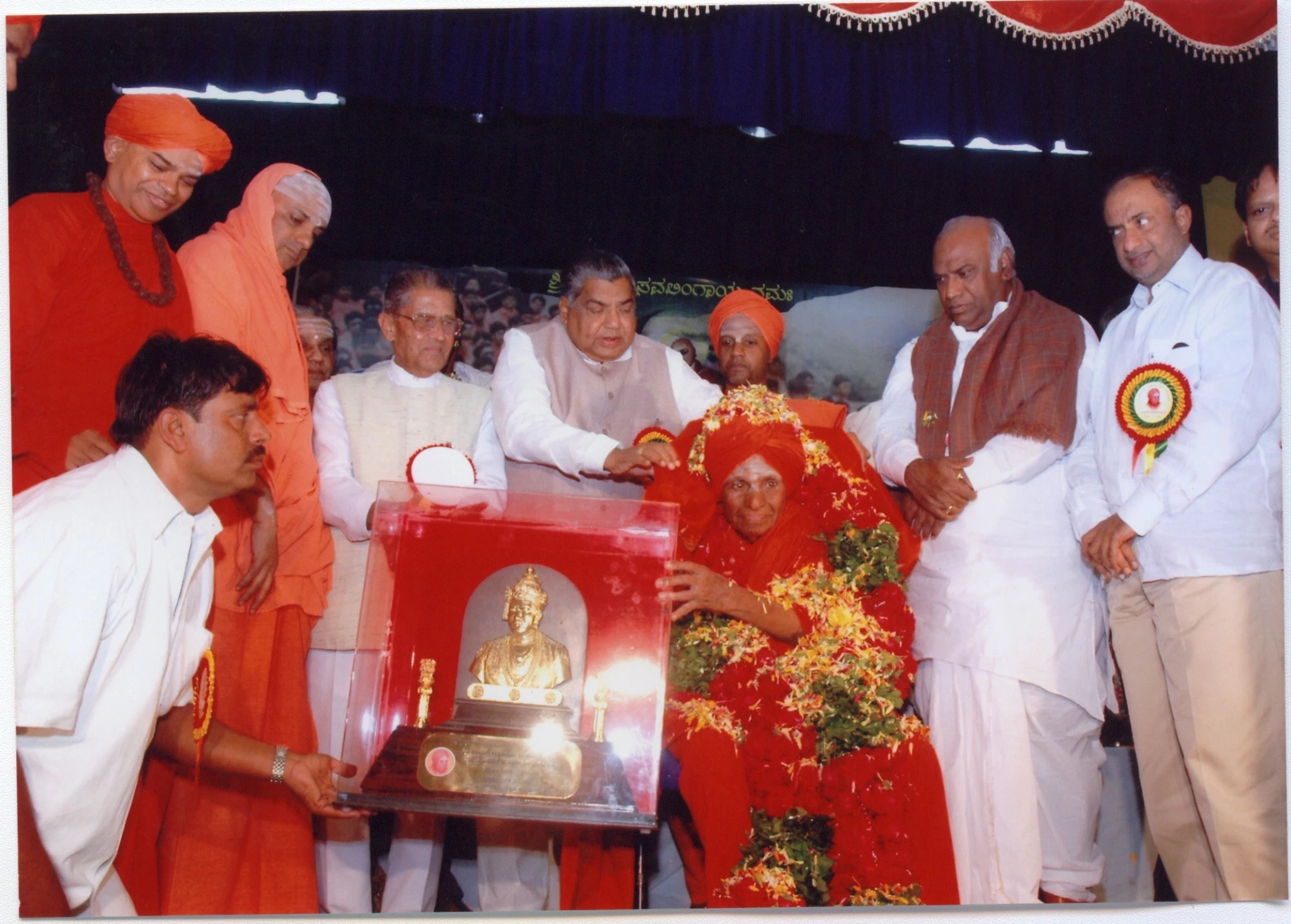 Public guests gathered around a ceremonial presentation with a revered Swamiji