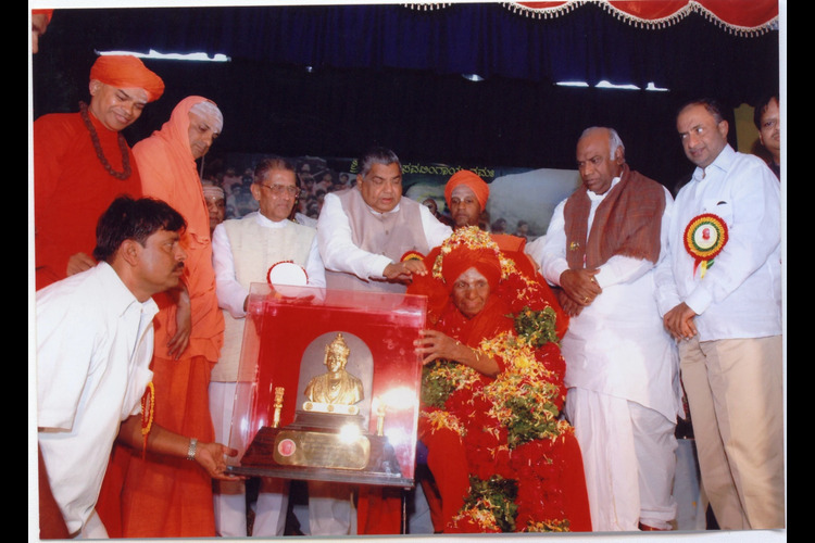 Revered Swamijis and guests gathered around a ceremonial presentation